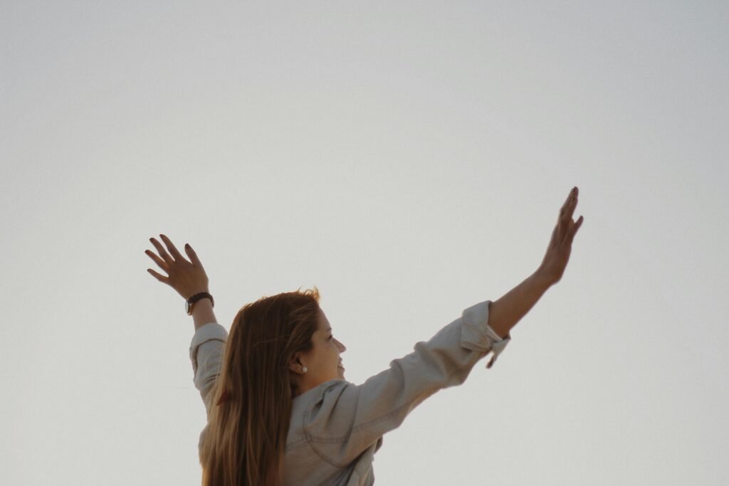 A woman with outstretched arms enjoys the sense of freedom and happiness outdoors.